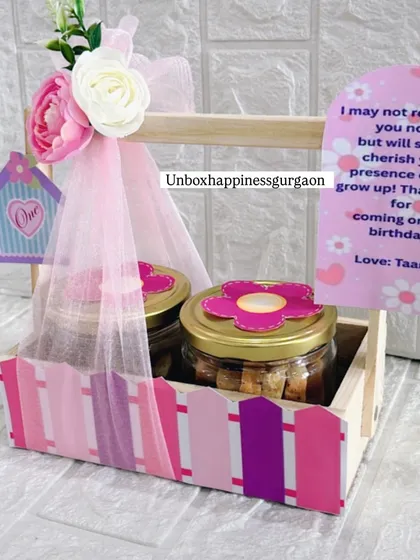 Another look at the pink birdhouse-themed return gift, highlighting the personalized card and the floral details on the basket.