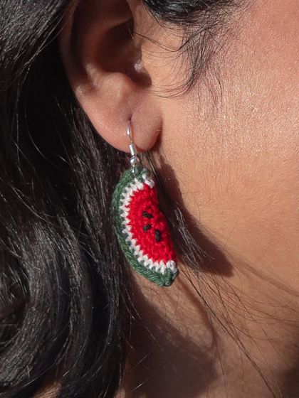 A detailed shot of the watermelon earring, showing the hand-stitched seeds and the different shades of green in the rind.