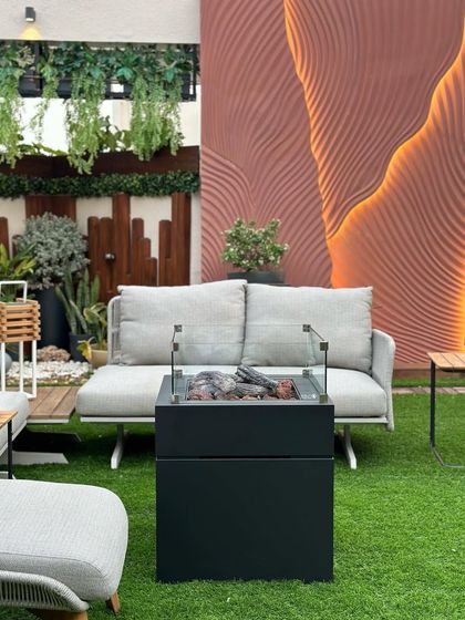 A frontal view of the modern firepit and sofa on the terrace. The design combines the warmth of a fire feature with the comfort of an indoor lounge, all in an outdoor setting.