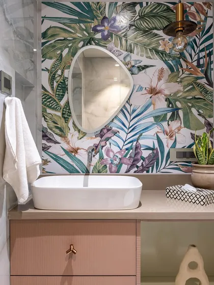 A beautiful blend of nature and modern design. This bathroom features a vibrant tropical leaf wallpaper, which serves as a stunning backdrop for the simple, elegant vessel sink and organic-shaped mirror.