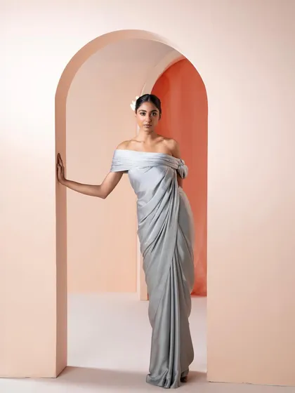 A stunning grey satin pre-draped saree with an off-shoulder blouse. This is the epitome of modern, minimalist glamour for cocktail events.