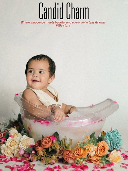 A 'Blissful Bath' theme for a sitter session. This baby enjoys a milk bath in a clear tub surrounded by colorful flowers, with a text overlay adding a charming, magazine-like feel.