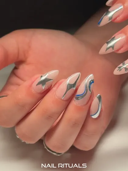 Celestial energy crafted to captivate. This close-up shows the sharp, metallic star and swirl designs on an elegant almond-shaped nail.