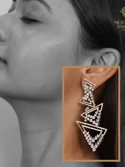 Modern and geometric. These dangling earrings feature a series of interconnected, diamond-encrusted triangles, creating a sharp and contemporary look.