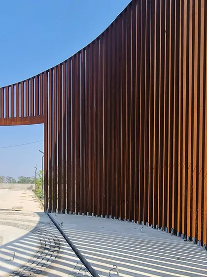 The play of light and shadow through the Corten steel screen is a key element of the design, transforming the structure throughout the day.