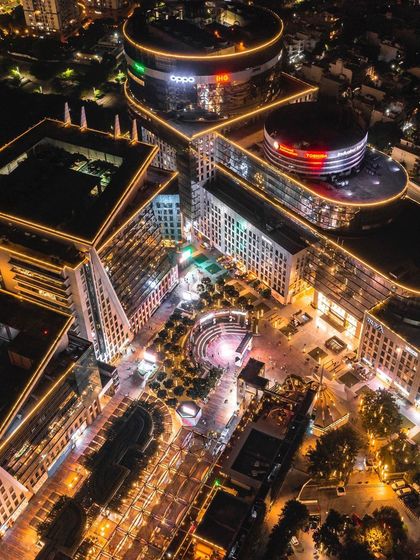 A top-down aerial photo of a brightly lit commercial complex in Gurgaon at night, highlighting its modern architecture and landscape design.