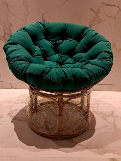 The Papasan chair, a classic piece of rattan furniture, is shown here with a large, comfortable tufted green cushion. Its bowl-shaped frame allows you to curl up and relax, making it a favorite for casual living spaces.