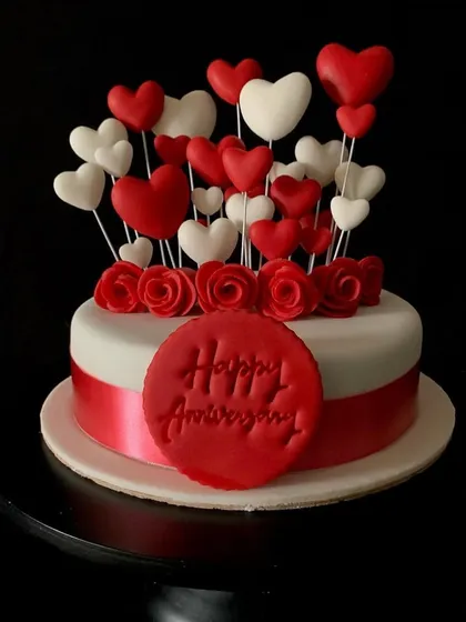 A beautiful anniversary cake covered in a bouquet of red and white fondant hearts.