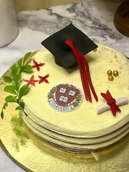 Celebrate academic achievements with a custom graduation cake. This one, for a Harvard grad, features a handcrafted graduation cap, a diploma, and the university crest, making for a proud and delicious centerpiece.