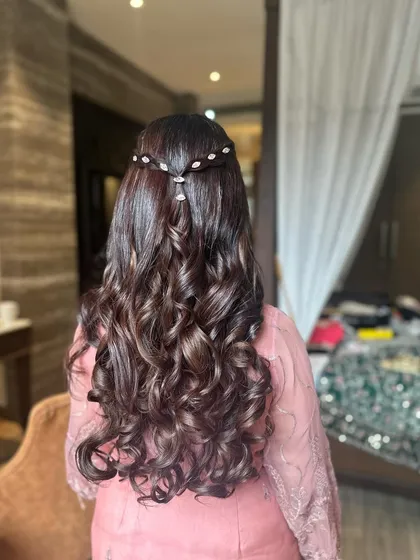 A half-updo with big, defined curls and a delicate, sparkling hair accessory. This is a popular choice for engagements and receptions.