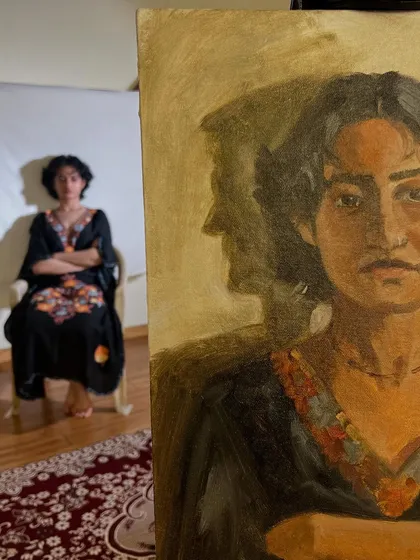 A view of the finished portrait next to the model, Anamaya. The shadow she casts on the wall behind her became an interesting compositional element in the final piece.