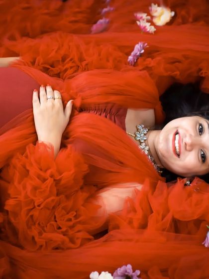 A creative overhead shot of a mom-to-be lying in a sea of red tulle. This artistic approach creates a stunning, abstract portrait that is full of color and texture.