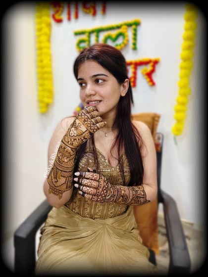 A beautiful candid shot of the bride during her mehndi ceremony, with a "Shaadi wala ghar" sign in the background.