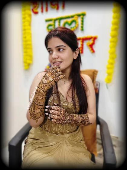 A beautiful candid shot of the bride during her mehndi ceremony, with a "Shaadi wala ghar" sign in the background.