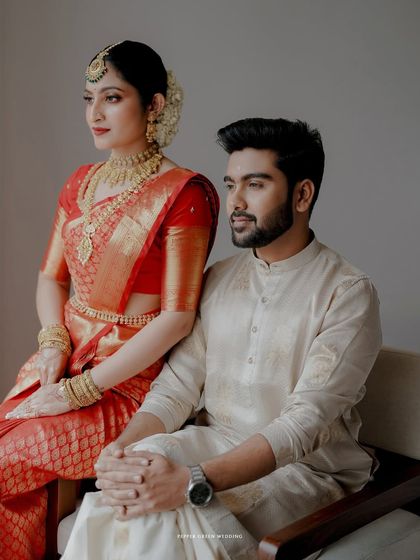 An elegant and poised portrait of the couple in their traditional red and cream wedding attire.
