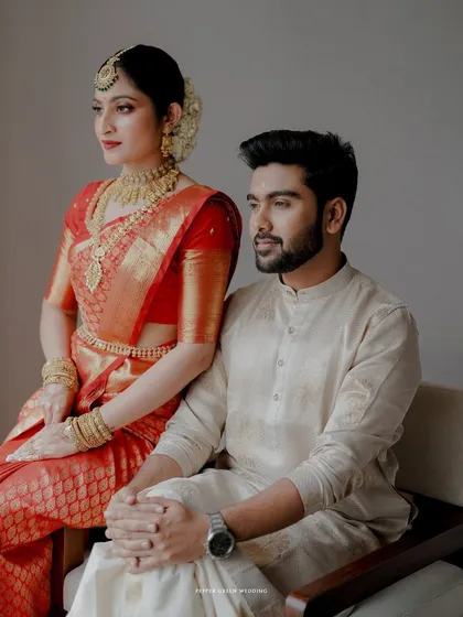 An elegant and poised portrait of the couple in their traditional red and cream wedding attire.