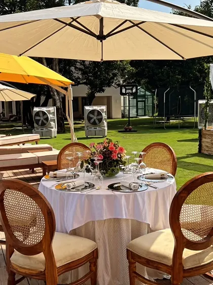 A perfect setup for a sunny winter brunch. A classic wooden dining set with an umbrella on a patio, ready for a relaxed mimosa-filled afternoon.