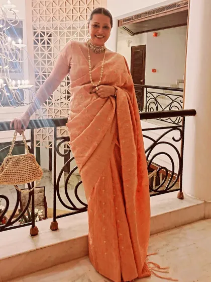 Another view of this elegant peach saree, perfect for a wedding reception or festive gathering. The delicate fabric and soft color are universally flattering.