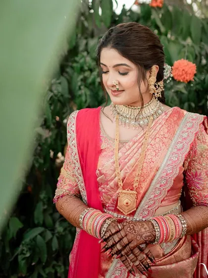 A close-up of the bride's engagement look. The makeup features soft, earthy tones that complement her pink and gold saree beautifully.