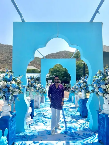 Posing in front of the stunning blue-themed decor for a Haldi carnival. The visual setup is just as important as the entertainment.
