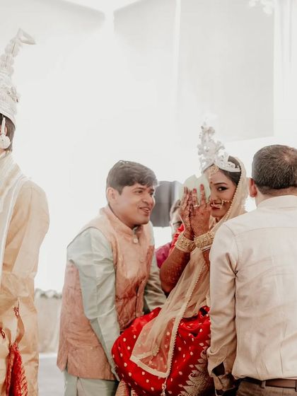 A candid moment from a Bengali wedding, capturing the "Shubho Drishti" ritual where the bride is lifted and sees the groom for the first time.