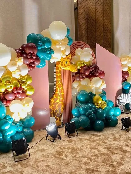 A full view of the modern jungle setup, highlighting the giraffe and zebra props alongside the colorful balloon arch.