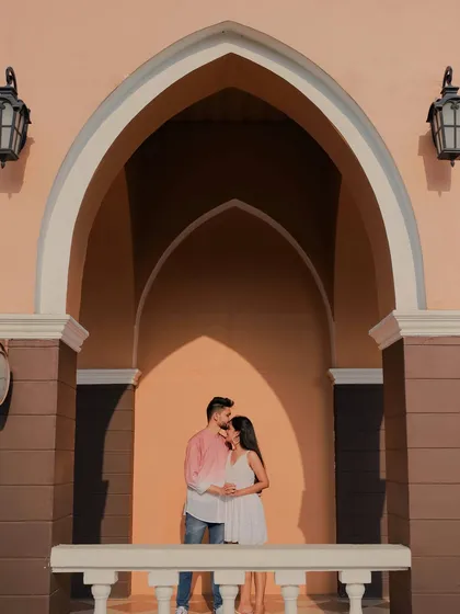 A beautifully composed shot using architectural arches to frame the couple. The warm light and the tender forehead kiss create a deeply romantic and artistic pre-wedding portrait.