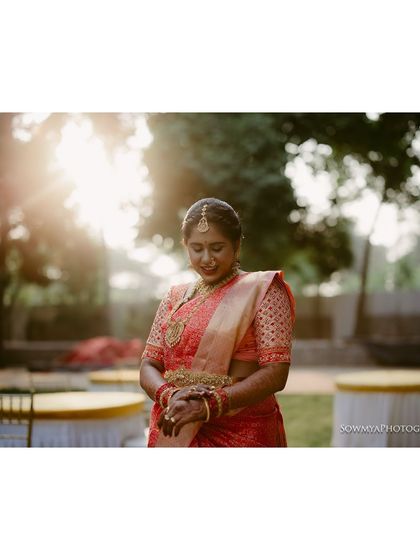 A serene bride in a red saree, captured in beautiful, soft backlighting. This portrait has a calm and ethereal quality.