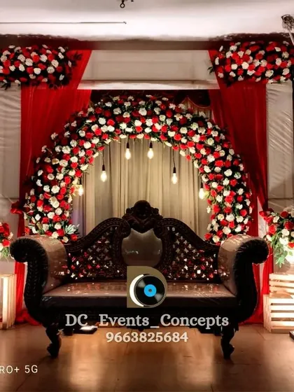 A full view of the red and white floral arch engagement stage. The matching floral arrangements on illuminated pedestals complete this elegant and classic look.