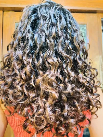 Chocolate Mocha Swirls are perfect for adding warmth and movement. This no-bleach balayage technique ensures the curls remain hydrated and bouncy post-coloring.