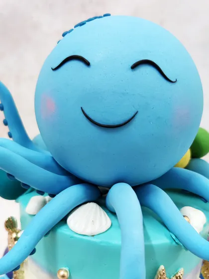 A close-up of the joyful blue octopus topper, with its sweet smiling face and rosy cheeks, ready to be the star of the party.