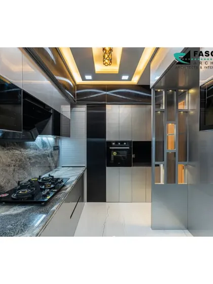 This ultra-modern kitchen in Seawoods features sleek, metallic-finish cabinets and a stunning grey marble-patterned backsplash that extends up the wall. A decorative ceiling with a gold-finish light fixture adds a luxurious final touch.