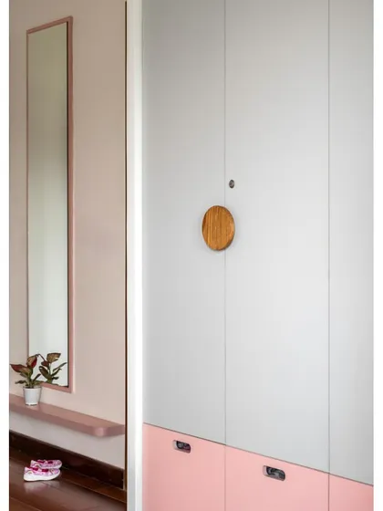 This wardrobe in the 'Vasudhalayah' daughter's room features a playful pink and grey color-blocked design with a unique circular wooden knob.