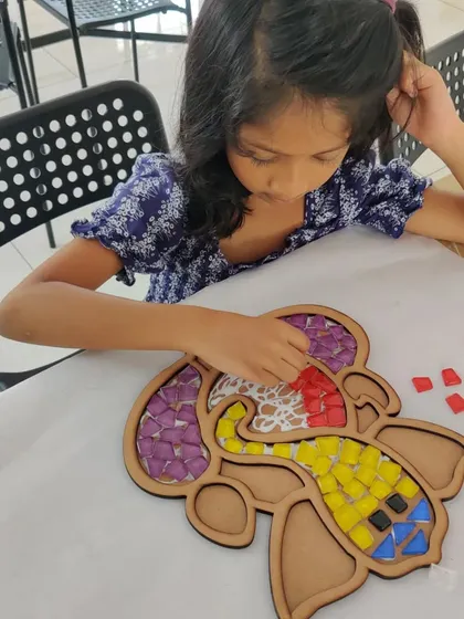 A young girl works on a vibrant Ganesha mosaic piece, another one of our popular DIY decor activities for Diwali.