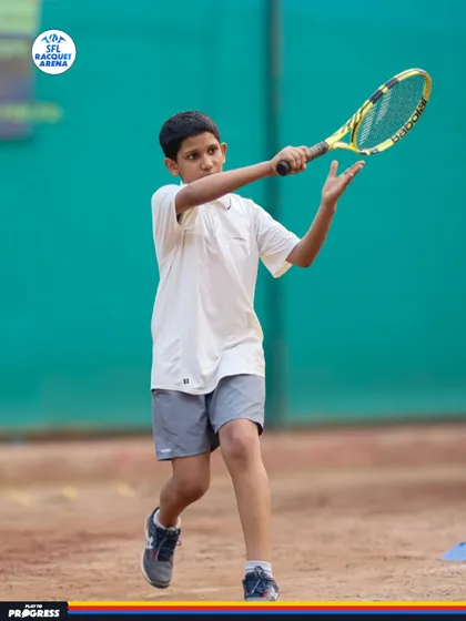 Perfecting the serve is a critical part of the game. Here, a young player practices his ball toss and swing, building the muscle memory needed for a powerful and consistent serve.