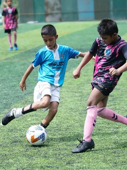 A skillful display of ball control as our player shields the ball from a defender from the opposing team.