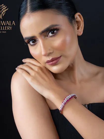 A delicate bracelet with a line of vibrant rubies flanked by sparkling diamonds, worn elegantly on a model's wrist.