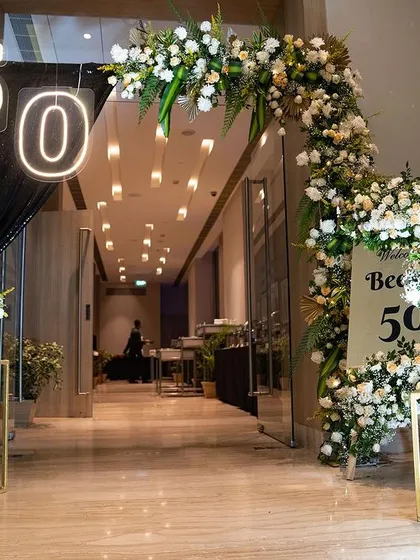 For a glamorous 50th birthday, I designed this grand entrance to set a tone of sophistication and excitement. The combination of lush white florals, dramatic black draping, and modern neon lighting created a truly fabulous welcome for the guest of honor and her friends.