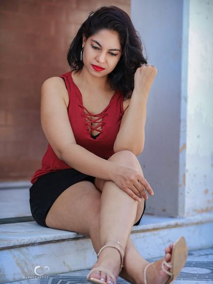 A quiet, contemplative moment on a set of steps. The natural light is soft and flattering, and the pose feels natural and unforced.