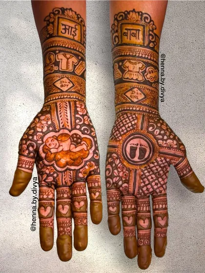 A sweet and symbolic baby shower mehendi. One hand features a baby sleeping on a cloud, while the other has tiny footprints, with 'Aai' and 'Baba' written on the forearms.