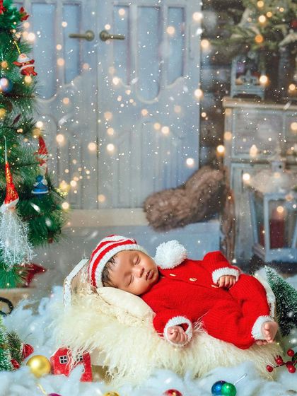 A cozy Christmas scene with the baby sleeping peacefully amidst festive decorations. The soft lighting and falling snow effect add a touch of holiday magic.