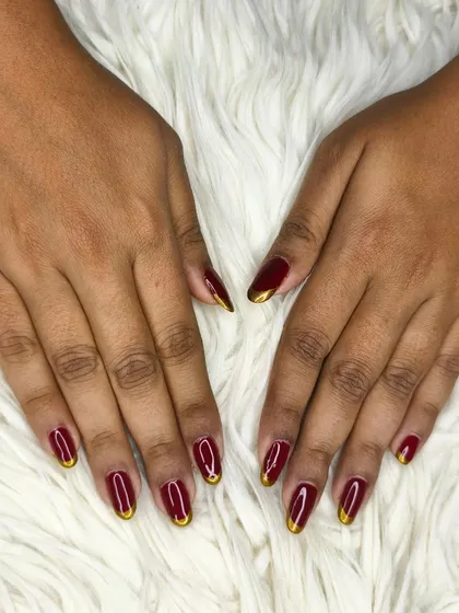 A full view of the maroon and gold French tip nails, showing their elegant shape and high-gloss finish.