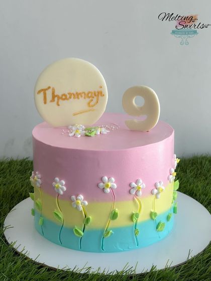 A simple no-fondant cake with hand-piped flowers, custom-designed by the birthday girl herself. The name and number are made of white chocolate.
