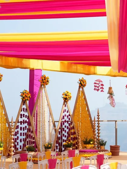 We bring vibrancy to tradition with setups like this stunning outdoor Haldi ceremony. The brilliant pink and yellow drapes create a joyful canopy, while the intricate marigold backdrops and floral arrangements set the stage for a day filled with laughter and blessings.