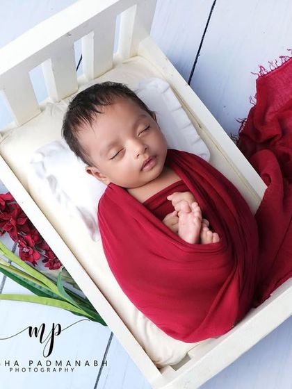 The baby is now resting peacefully in the bed, swaddled in red.