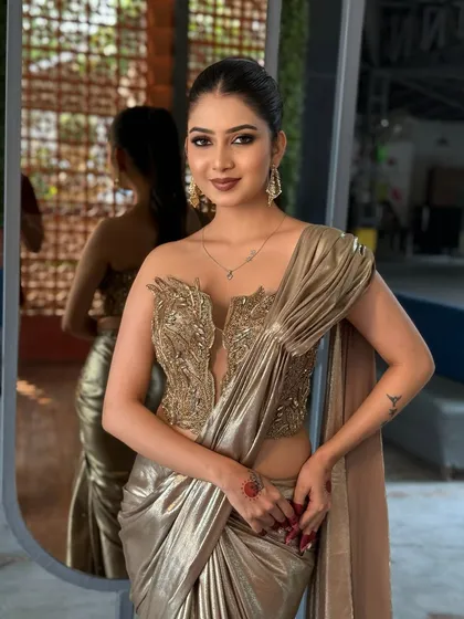 A portrait of the model, her confident pose matching the bold, golden outfit.