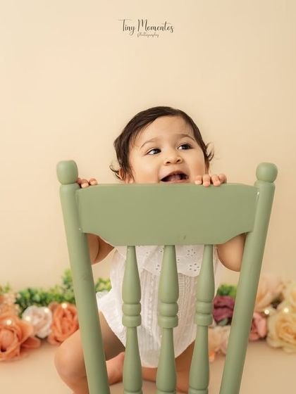 A playful game of peek-a-boo. I love incorporating simple props like this chair to encourage interaction and capture genuine expressions.