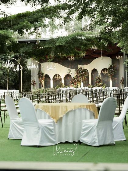 A wide shot of a royal romance-themed wedding. The garden is transformed with elegant seating, chandeliers, and a beautifully decorated stage, creating a fairytale atmosphere.