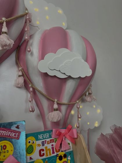 A close-up of the pink and white hot air balloon lamp, showing the delicate tassels and cloud detail.