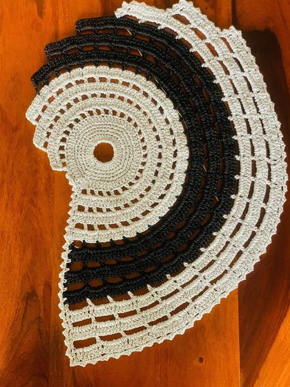 This unique semi-circular centerpiece features a yin-yang inspired design in black and beige. It's a modern and artistic piece for a console or side table.